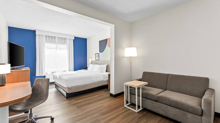 King guest room with sofa, desk, and television